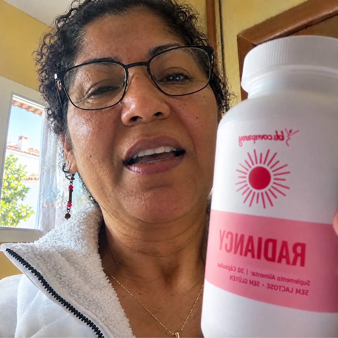 Mulher de cabelo curto e óculos a segurar um frasco branco com rótulo cor-de-rosa onde se lê "RADIANCY".